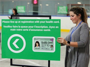 A worker places a sign as medical staff members prepare to receive patients for coronavirus screening at a temporary assessment centre at the Brewer hockey arena in Ottawa.