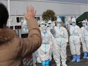 Medical personnel in protective suits wave hands to a patient who is discharged from the Leishenshan Hospital after recovering from the novel coronavirus, in Wuhan, the epicentre of the novel coronavirus outbreak, in Hubei province, China March 1, 2020. Picture taken March 1, 2020.