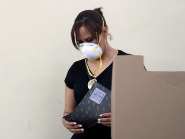 A woman wearing a protective mask prepares a ballot as people wait to cast their votes for nationwide municipal elections amid concerns over the spread of coronavirus disease (COVID-19), at a polling station in Santo Domingo, Dominican Republic, March 15, 2020.