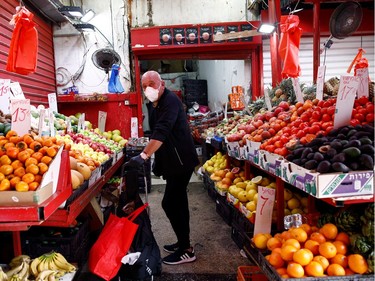 A man wearing a mask shops at a food market after Israeli Prime Minister Benjamin Netanyahu's government announced that malls, hotels, restaurants and theaters will shut down from Sunday, in an escalation of precautionary measures against coronavirus, in Tel Aviv, Israel March 15, 2020.