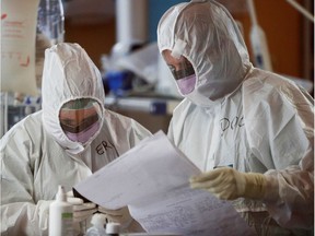 Medical workers in protective suits check a document as they treat patients suffering with coronavirus disease (COVID-19) in an intensive care unit at the Casalpalocco hospital, a hospital in Rome that has been dedicated to treating cases of the disease, Italy, March 24, 2020.