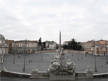 People walk by an almost empty Piazza del Popolo as the Italian government continues restrictive movement measures to combat the coronavirus outbreak, in Rome, Italy March 14, 2020.
