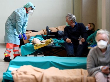 Medical personnel wearing protective face masks help patients inside the Spedali Civili hospital in Brescia, Italy March 13, 2020.