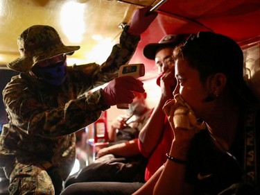 A police officer checks a jeepney passenger's body temperature at a checkpoint placed amidst the lockdown of the country's capital to contain the spread of coronavirus, in the outskirts of Quezon City, Metro Manila, Philippines, March 15, 2020.