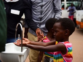 Twin sisters, Emeline and Eveline, wash their hands at a public hand washing station as a cautionary measure against the coronavirus at Nyabugogo Bus Park in Kigali, Rwanda. March 11, 2020. REUTERS/Maggie Andresen