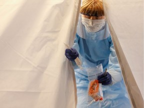 Nurse Becky Barton walks out of a tent with a test kit at a drive-through testing for coronavirus, flu and RSV, currently by appointment for employees at UW Medical Center Northwest in Seattle, Washington, U.S. March 9, 2020.