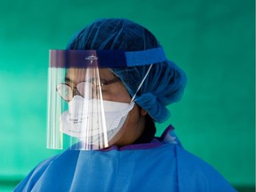 A nurse dons protective gear.