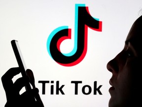 FILE PHOTO: A person holds a smartphone as Tik Tok logo is displayed behind in this picture illustration taken November 7, 2019. Picture taken November 7, 2019. REUTERS/Dado Ruvic/Illustration/File Photo ORG XMIT: FW1