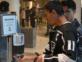 Fans use a hand sanitizer station at the Staples Center before a game between the Los Angeles Kings and the Ottawa Senators on Wednesday, March 11, 2020.