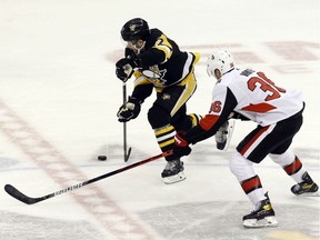 Pittsburgh Penguins right wing Bryan Rust moves the puck as Ottawa Senators center Colin White defends during the second period at PPG PAINTS Arena on Tuesday.