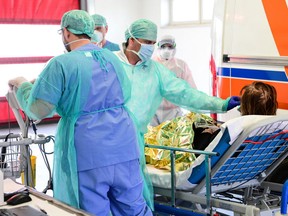 A medical worker wearing a face mask tens to a patient arriving on a stretcher at the new coronavirus intensive care unit of the Brescia Poliambulanza hospital, Lombardy, on March 17, 2020.