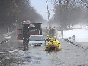 Ottawa Fire Services work to rescue the driver of a school minivan trapped on a flood road in Metcalfe Tuesday morning