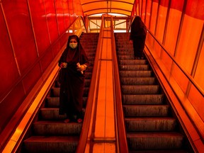 A pedestrian wears a protective face mask while travelling down a walkway escalator in Tehran, Iran, on Sunday, March 15, 2020. Iran's President Hassan Rouhani announced a series of banking, welfare and tax relief measures to support business and families as the coronavirus outbreak puts severe strain on the economy.