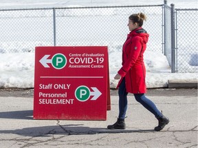 A woman walks past a sign for the COVID-19 Assessment centre at Brewer Arena which had steady traffic on Wednesday morning.    Photo by Wayne Cuddington / Postmedia