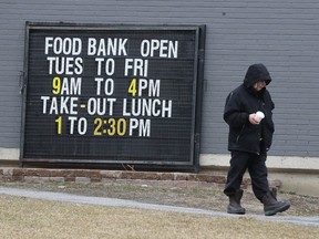 A man walks past a food bank sign on Caldwell Ave. in Ottawa Tuesday March 31, 2020.