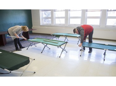 Mayor Jim Watson tours the isolation centre for vulnerable residents ahead of its opening on Monday with Wendy Muckle, executive director of Ottawa Inner City Health, and members of the Human Needs Taskforce, seen here setting up cots in a former classroom that will become a dormitory.