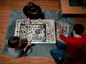Members of a flat-sharing lay a puzzle at their living room in Dortmund, western Germany, on March 27, 2020, amidst the pandemic of the new coronavirus COVID-19.