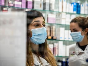 Pharmaceutical workers wear face masks to serve customers in a pharmacy.