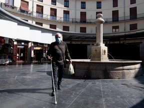 A man wearing a protective mask walks in Valencia, Spain, on Saturday, March 14, 2020.