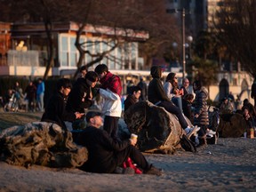 People take in the sunset at English Bay Beach, in Vancouver, on Saturday, March 21, 2020. The City of Vancouver asked those coming to the park and beach to maintain a distance of two metres between one another due to concerns about the spread of the coronavirus.