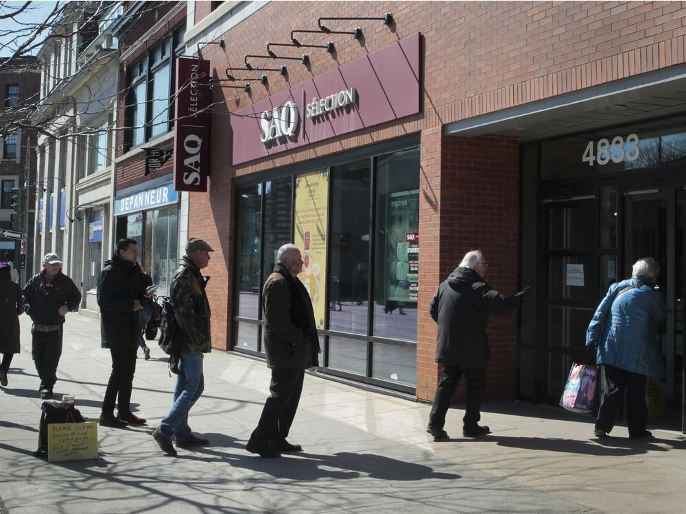 Files: People line-up outside an SAQ location in Westmount on March 21, 2020.