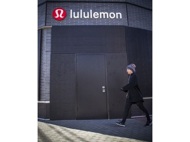 OTTAWA -- April 11, 2020 -- A woman walks by the boarded up Lululemon store in Westboro, Saturday, April 11, 2020.