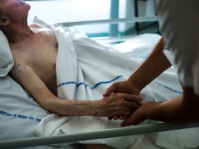 A nurse holds the hand of a patient at the palliative care unit of the Argenteuil Hospital in Paris. It is wise to ensure your family and substitute decision-maker know your end-of-life wishes.