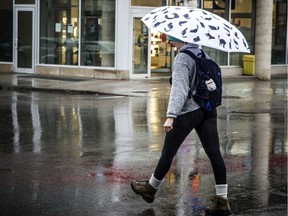 Pedestrians make their way along Bank Street in the rain, Sunday, March 29, 2020.