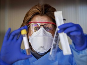 A medical staff displays a test kit to detect the novel coronavirus at a COVID-19 screening-drive, at the  Amsterdam UMC in Amsterdam The Netherlands, on March 24, 2020.
