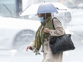 A woman wearing a facemask crosses the street.