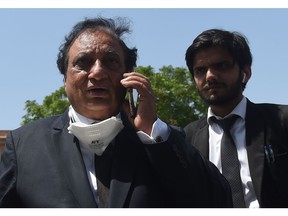 Khawja Naveed (L), defence lawyer of Omar Sheikh, who was convicted to death sentence over the killing of US journalist Daniel Pearl, speaks on his cellphone outside the High Court builiding in Karachi on April 2, 2020. - A Pakistani court on April 2 overturned the death sentence for British-born militant Ahmed Omar Saeed Sheikh, who had been convicted over the 2002 killing of American journalist Daniel Pearl.