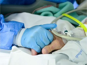 FILE: A healthcare worker comforts and holds the hand of a patient infected by the novel coronavirus.