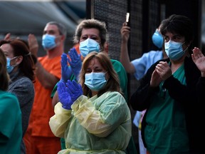 Heathcare workers applaud in return as they are cheered on outside the Gregorio Maranon Hospital in Madrid on April 12, 2020 during a national lockdown to prevent the spread of the COVID-19 disease.
