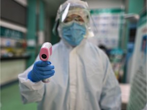 A medical worker prepares to check the temperature of an AFP photojournalist before a COVID-19 coronavirus test in Wuhan.