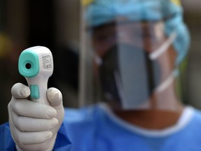 A health worker wearing a biosafety suit takes the temperature of a man during a checkup.