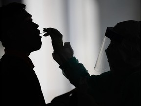 A health worker uses a swab to collect a sample for COVID-19 coronavirus testing from a man in Gombak on the outskirts of Kuala Lumpur on April 22, 2020.