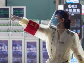 A staff member wearing a face shield gestures at a long-distance bus station in Wuhan in China's central Hubei province on April 30, 2020, ahead of the Labor Day holiday which starts on May 1.