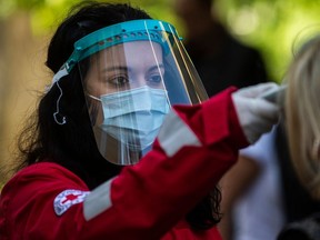 A Hellenic Red Cross volunteer wearing personal protective equipment checks the temperature of people entering the premises of a court in Athens on April 30, 2020.