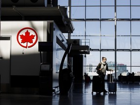 A passenger wheels her luggage near an Air Canada logo at Toronto Pearson International Airport on April 1, 2020 in Toronto.