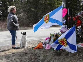 Denise Caume and her dog pause in front of a makeshift memorial, made in the memory of the mass shooting in Portapique, Nova Scotia.