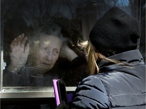 A woman visits her 86-year-old mother through a window at the Orchard Villa long-term care home in Pickering on Wednesday April 22, 2020. The Pickering home was one of the homes included in a shocking report by the Canadian military, released Tuesday by the province, regarding the status of five homes in Ontario.