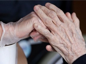 An employee holds the hand of a person at the elderly residence Christalain following the coronavirus disease (COVID-19) outbreak in Brussels, Belgium April 14, 2020. REUTERS/Yves Herman ORG XMIT: GDN