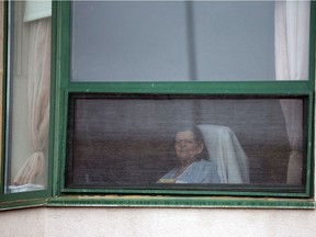 A resident looks out her window at Residence Herron, following a number of deaths at the Montreal-area long-term care facility.