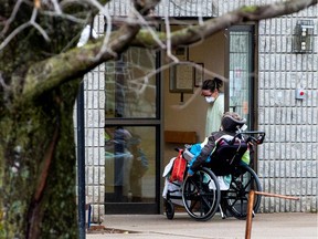 A woman opens the door to a person in a wheelchair at Pinecrest Nursing Home in Bobcaygeon, Ont.