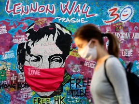 A woman walks past the now-masked John Lennon Wall as the spread of the coronavirus disease (COVID-19) continues in Prague, Czech Republic.