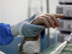An intubated patient tries to gesture at a medical worker holding his hand at the intensive care unit (ICU) of the Sotiria hospital, following the coronavirus disease (COVID-19) outbreak, in Athens, Greece, April 25, 2020. Picture taken April 25, 2020.