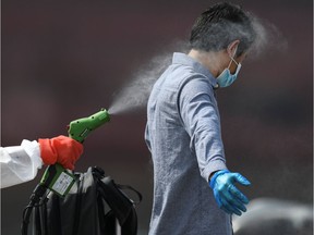 A medical staff sprays disinfectant on a crew member of the Explorer Dream cruise ship on arrival at JICT port amid the spread of the coronavirus disease (COVID-19) in Jakarta, Indonesia April 29, 2020.