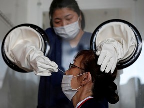 A medical worker performs a walk-in style polymerase chain reaction (PCR) training test for the coronavirus disease (COVID-19), at a makeshift facility in Yokosuka, south of Tokyo, Japan, April 23, 2020.