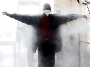 FILE PHOTO: A passenger walks through a disinfectant tunnel following social distancing rules as he prepares to board the commuter train service by the Kenya Railways Corporation before a curfew, as a measure to contain the spread of the coronavirus disease (COVID-19), at the main railway station in downtown Nairobi, Kenya April 29, 2020.