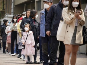 People wearing masks in an effort to prevent the spread of the coronavirus disease (COVID19) wait in line to cast their ballots at a polling station in Seoul on Wednesday.